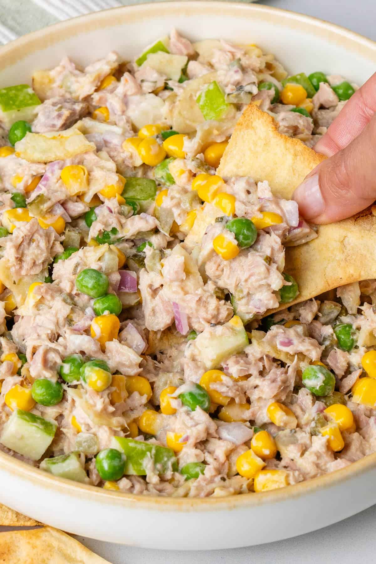 Pita chip dipped into tuna salad bowl